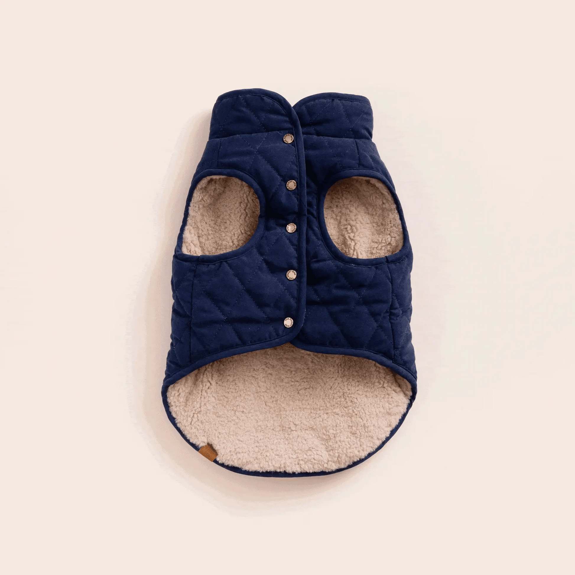 The Foggy Dog Navy Sherpa-Lined Reversible Dog Jacket, Large, features snap buttons, beige sherpa lining, two armholes, and a curved hem.