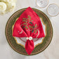 Kim Seybert Holly Ribbon napkin in red linen with embroidered holly, cinched by a double pearl ring on a beaded green charger plate.