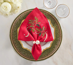 Kim Seybert Holly Ribbon napkin in red linen with embroidered holly, cinched by a double pearl ring on a beaded green charger plate.