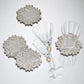 Four silver-beaded Winter Lace Coasters with round, leaf-like edges, two of which are topped with clear glass drinkware.