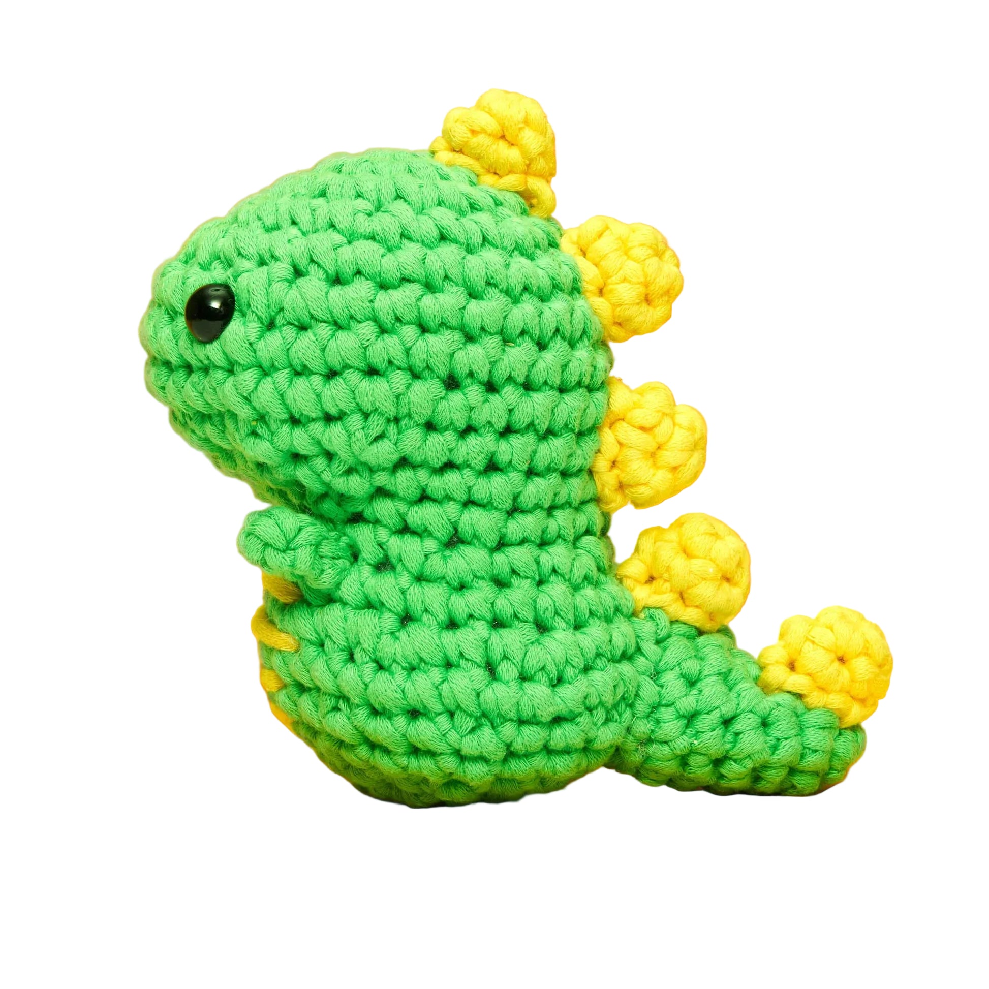 A small, green crocheted dinosaur toy with yellow spikes on its back, shown in profile against a white background. Crafted using the magic loop technique, The Woobles’ Fred the Dinosaur Beginner Crochet Kit makes a charming addition to any crochet collection.