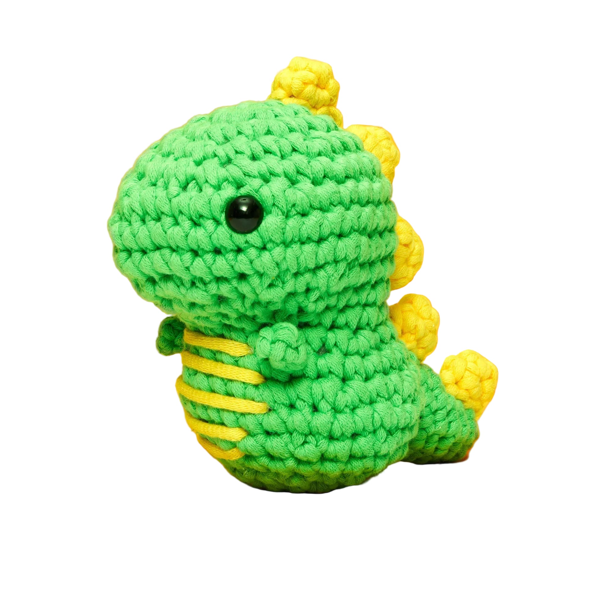 Fred the Dinosaur Beginner Crochet Kit by The Woobles features a green crocheted dinosaur plush, named Fred the Dino, with yellow spikes and belly stripes, made using the magic loop technique and displayed on a white background.