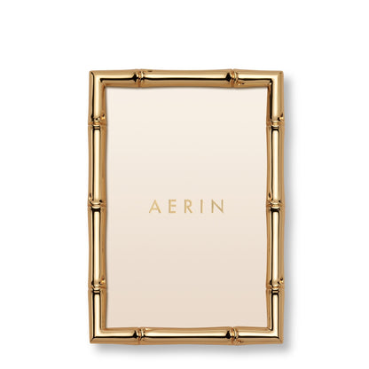 The Ava Bamboo Frame Collection by Aerin features a rectangular gold-finish frame with a bamboo-style design and a blank insert displaying "AERIN" at the center.