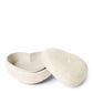The Aerin Shagreen Heart Box Collection features a textured, white oval keepsake box with a fitted lid, shown open to display its matching shagreen interior and exterior against a plain white background.