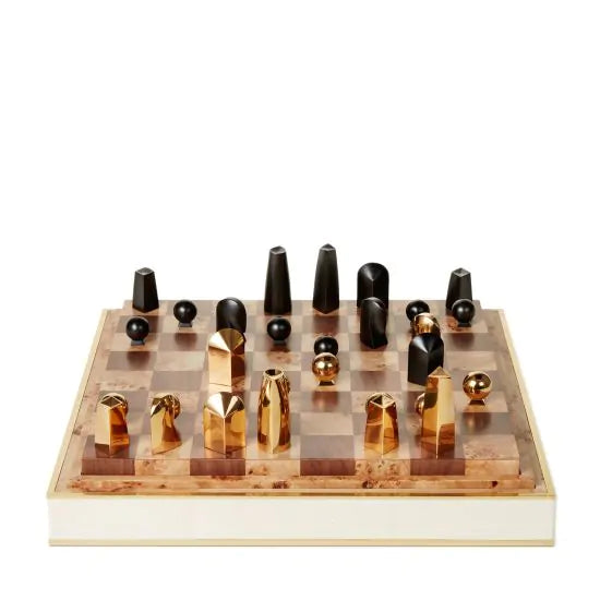 The Aerin Shagreen Chess Set Collection features gold-plated abstract chess pieces on a brown and beige checkered board, elegantly presented in a luxurious shagreen box.