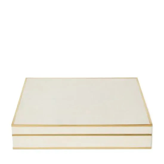 The Aerin Shagreen Chess Set Collection features a closed, rectangular cream-colored shagreen box with gold trim, displayed against a white background.