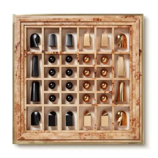 The Aerin Shagreen Chess Set Collection features gold-plated abstract chess pieces on a beige and brown marble board with a grid layout, all presented in a luxurious shagreen box.
