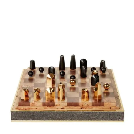 The Shagreen Chess Set Collection by Aerin features gold-plated geometric pieces on a brown and beige board, elegantly presented in a luxurious shagreen box.