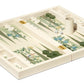 The AERIN x Gracie Heathcote Lacquer Backgammon Set features a Heathcote design with a floral motif board, white and green checkers, two dice, and dice shaker. It evokes elegant hand-painted wallpapers, blending artistry with classic gaming tradition.