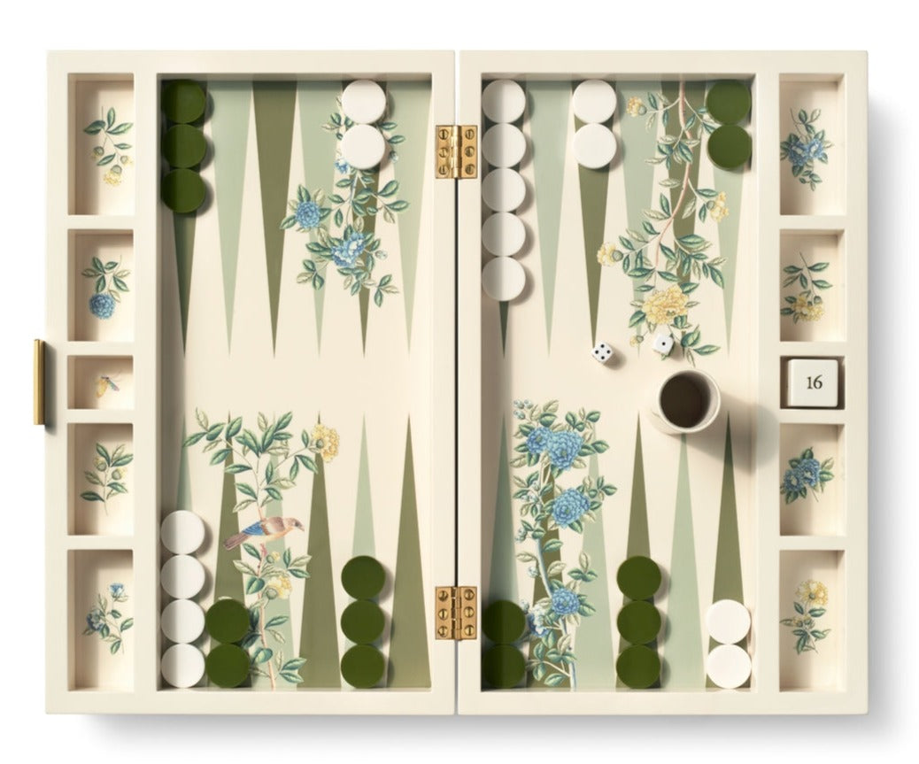 The AERIN x Gracie Heathcote Lacquer Backgammon Set by Aerin features a Heathcote design with green and white checkers, dice, a doubling cube on 16, and a cup, all set against a hand-painted wallpaper backdrop.