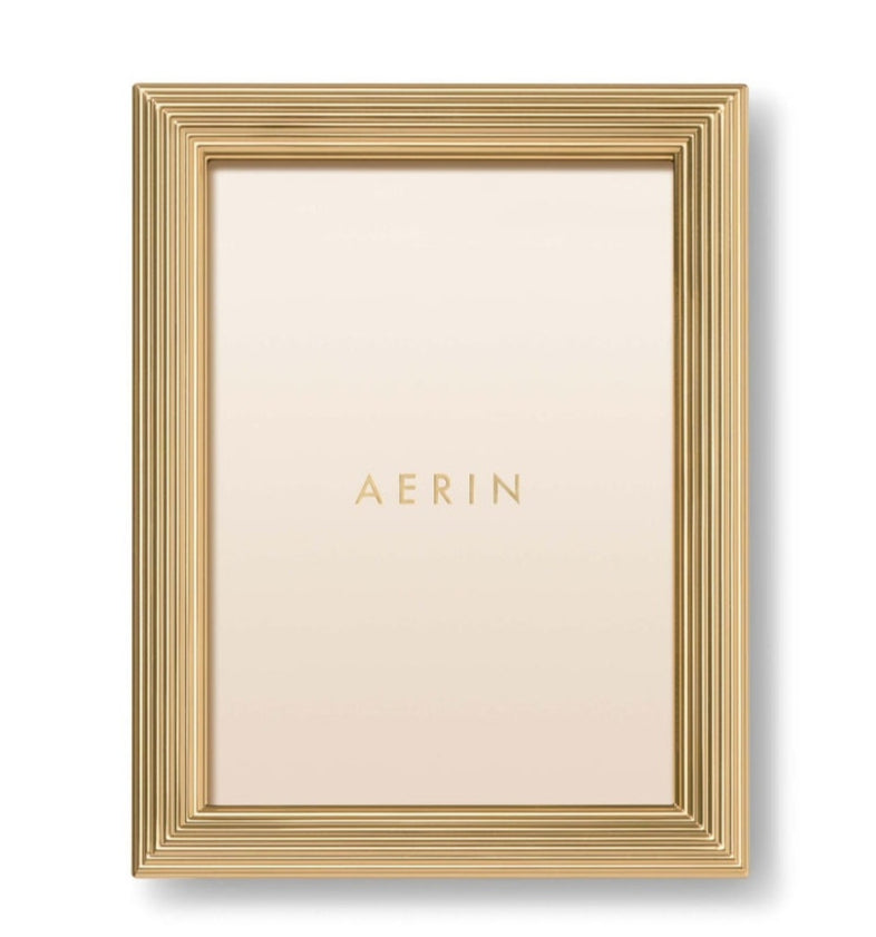 The Alessio Frame Collection by Aerin features a gold rectangular frame with a reeded border, shown vertically with a blank insert reading "AERIN"—a stylish choice for elegant photograph display.