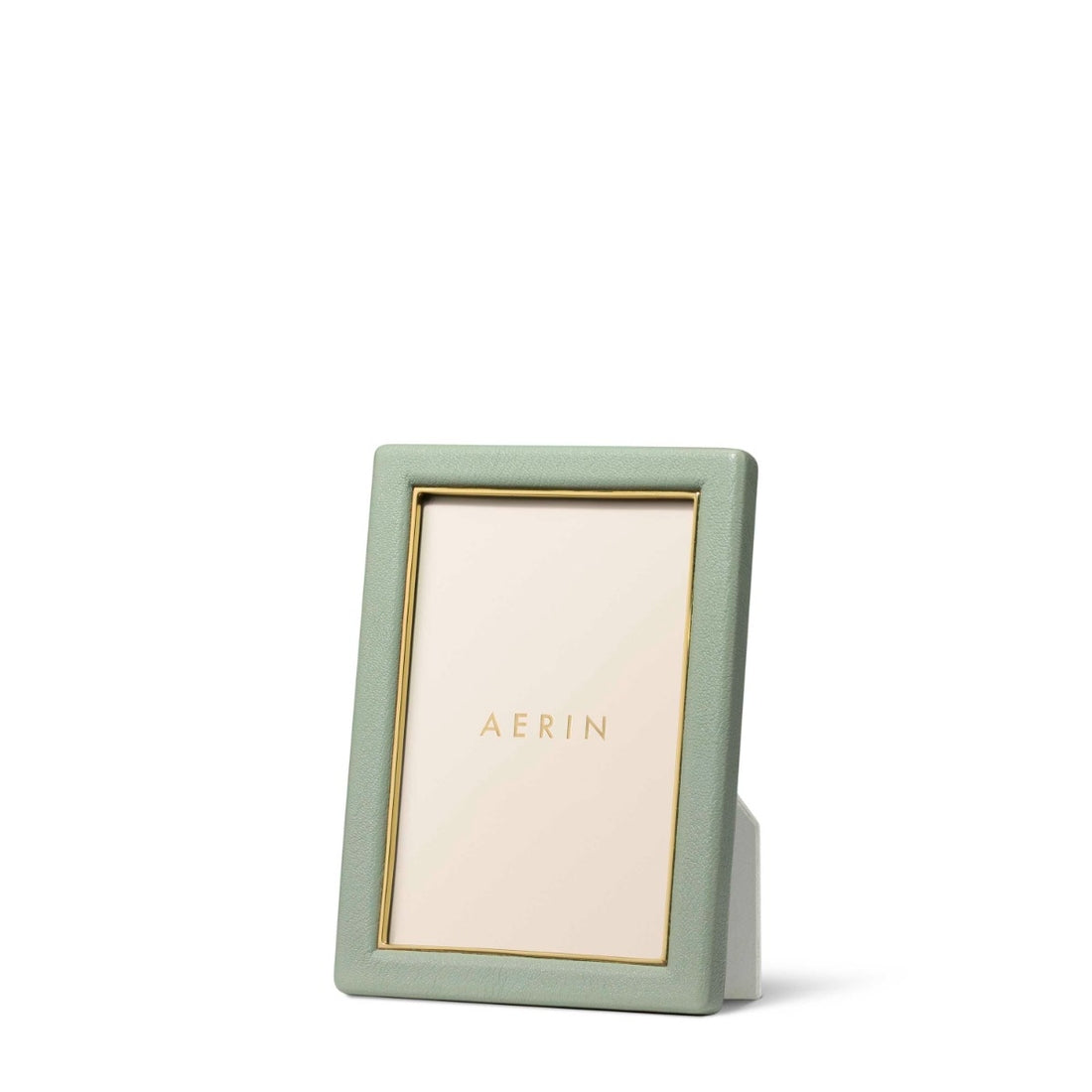 The Piero Leather Frame Collection by Aerin features a vertical green leather frame with gold accents and a gold inner border, displaying an "AERIN" placeholder card against a white background for an elegant touch.