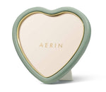 The Eucalyptus Piero Leather Heart Frame by Aerin features a light green leather border and gold trim, with the brand name "AERIN" in gold on a cream background—an elegant accent for any space.