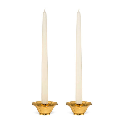 Two white taper candles stand in the Olivia Brass Taper Candleholder Set by Aerin, featuring elegant brass holders with a hint of Art Deco style, set against a plain white background.