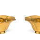 The Aerin Olivia Brass Taper Candleholder Set features two gold-toned, flower-shaped candleholders displayed side by side on a white background.