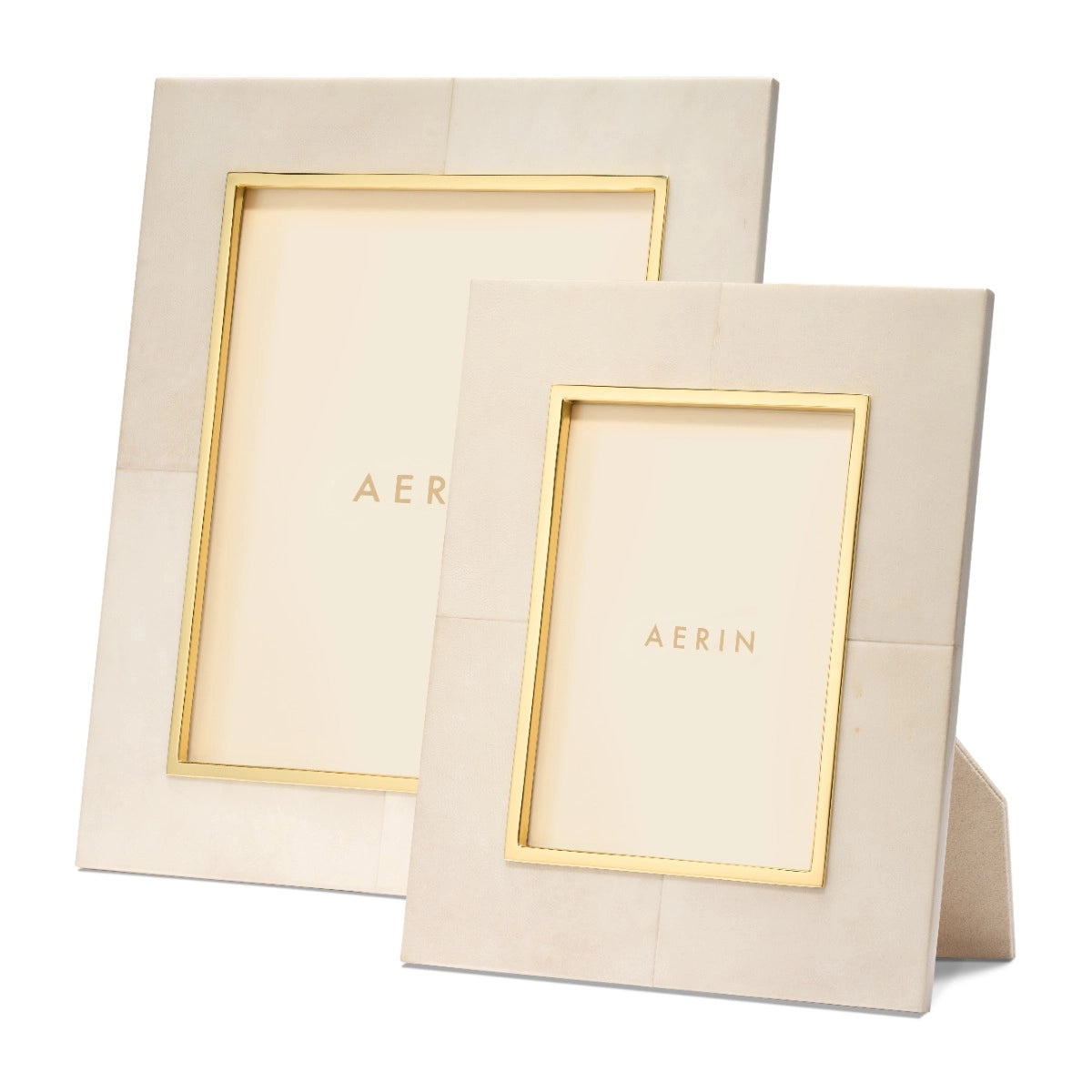 Two beige rectangular frames from the Aerin Livio Parchment Frame Collection, one large and one small, both upright with gold inner borders and brass accents, featuring "AERIN" on the placeholder inserts.