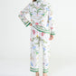 A person wearing Yves Delorme x Laurence Tavernier Botanic Pajamas featuring a colorful bird print and green striped cuffs.