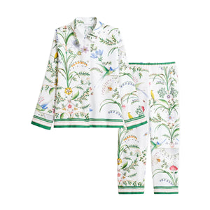 Yves Delorme x Laurence Tavernier Botanic button-down pajamas featuring a colorful floral, vine, and bird print on a white background with green striped trim.