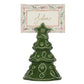 A green ceramic Berry & Thread Tree Place Card Holder holding a rectangular card with the name “John” printed in script.