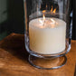 The Simon Pearce Ivory Candle Collection features a large, three-wick artisan candle in a clear glass holder, adding warmth and elegance to your home décor.