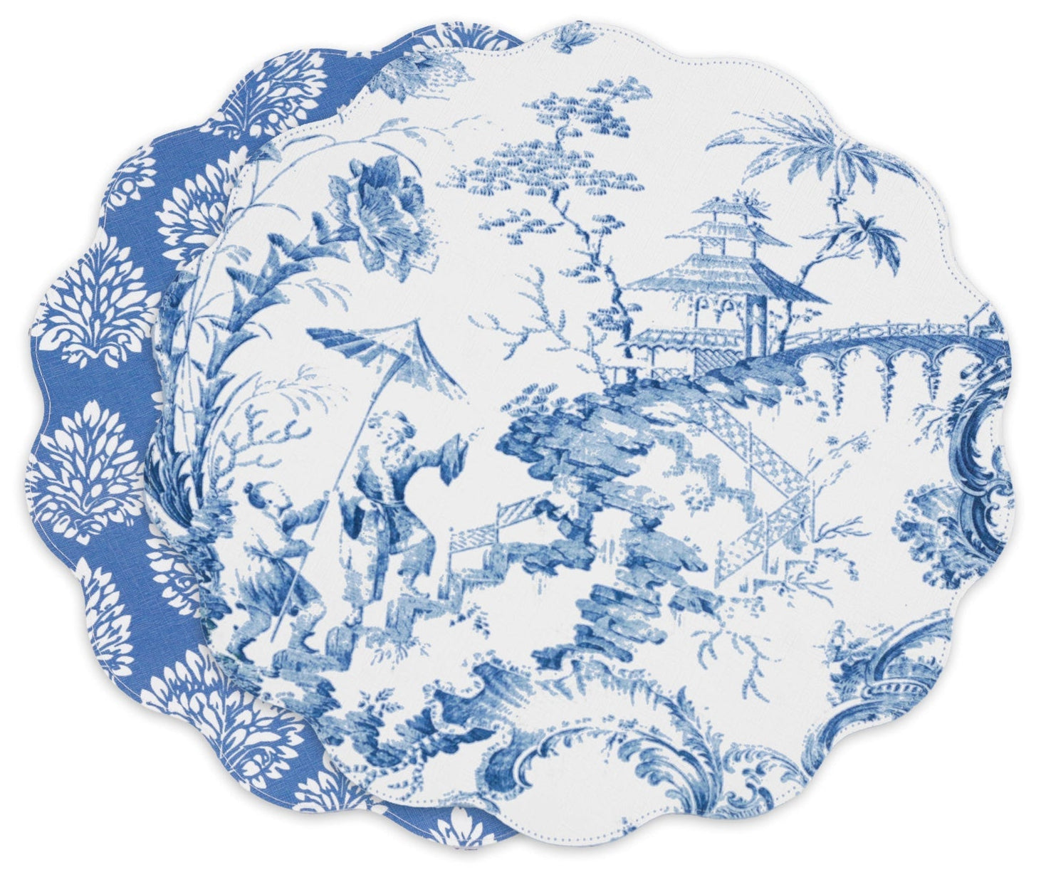 Two scalloped-edge plates—one with a blue-and-white pastoral scene, the other with a floral motif—pair beautifully with the Beatriz Ball VIDA Chinoiserie Reversible Round Placemat.