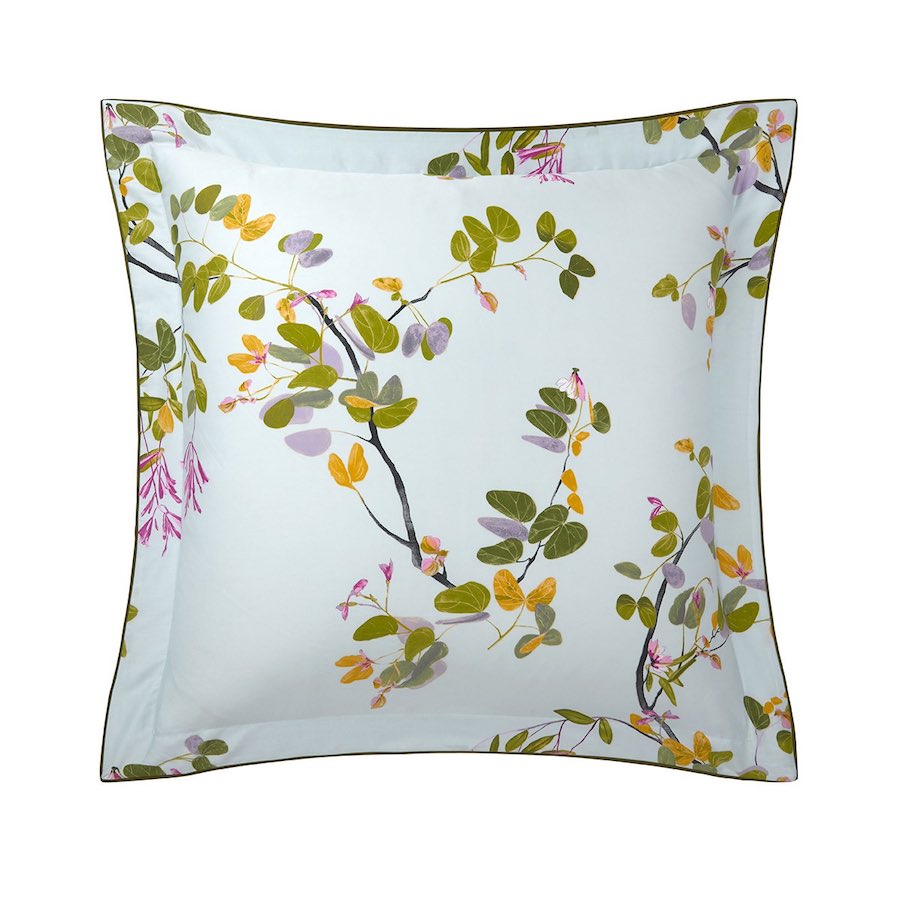 Square pillow from the Yves Delorme Luciole Bedding Collection, made of organic cotton sateen with a white background, botanical print in green, yellow, and pink, and finished with slender green piping.