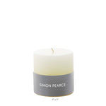 Ivory Candle Collection by Simon Pearce—an artisan, small-batch candle featuring a gray brand label. Perfect for bringing warmth and elegance to your home. Candle dimensions: 3" x 3". Photographed against a plain white background.