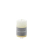 The Simon Pearce Ivory Candle Collection features a white pillar candle with a gray label, measuring 2" x 3". This artisan piece adds understated elegance to your home decor.