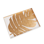 The Beatriz Ball Large Lacquered Philodendron Tray is a rectangular white serving tray with a bold gold philodendron leaf, perfect as a decorative accent or coffee table tray to add a touch of elegance to any space.