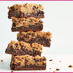 A stack of five thick chocolate chip cookie brownies is displayed against a plain background, with crumbs scattered around—perfect inspiration for anyone looking to explore creative cookies or discover new recipes from Martha Stewart’s Cookie Perfection by Penguin Random House.