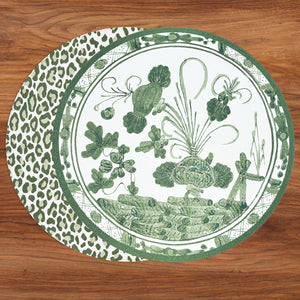 A round green and white Vida Faenza Melamine plate from Beatriz Ball, featuring a botanical design, partially overlaps a coordinating green leopard print placemat from the same collection on a wooden surface.