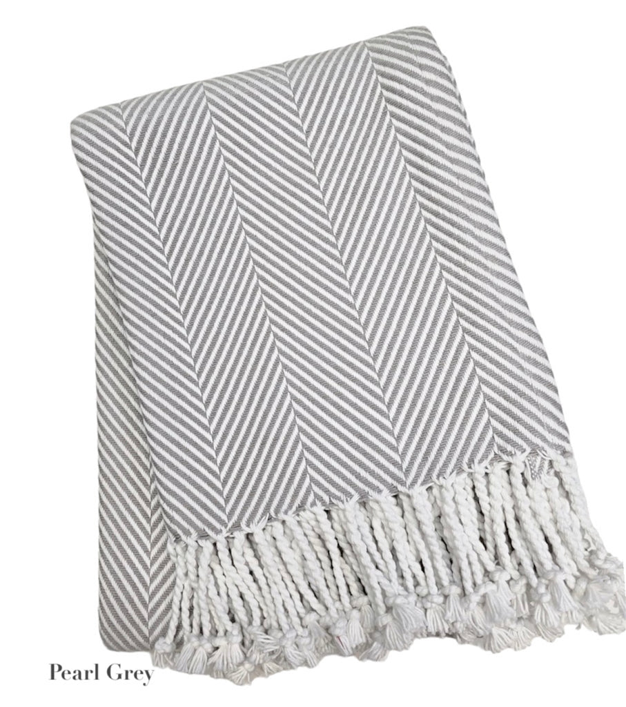 A Soft Idea Nantucket Herringbone Throw Collection in Pearl Grey, featuring a folded grey and white design with hand-knotted fringe, shown on a white background.