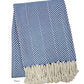 The Nantucket Herringbone Throw Collection by A Soft Idea features a folded navy and white throw with hand-knotted fringe, classic herringbone pattern, and soft cotton craftsmanship.