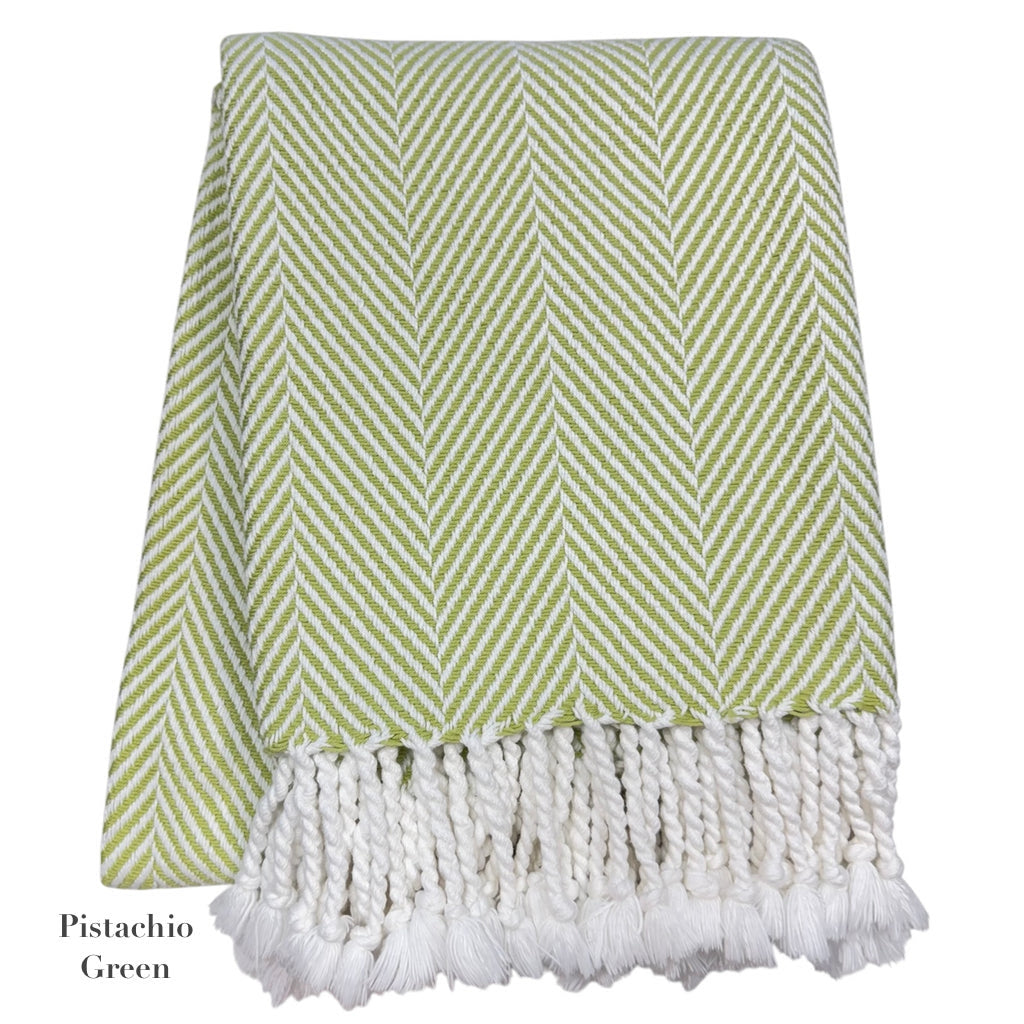 The Nantucket Herringbone Throw Collection by A Soft Idea features a pistachio green and white chevron design in soft cotton, finished with hand-knotted fringe tassels.