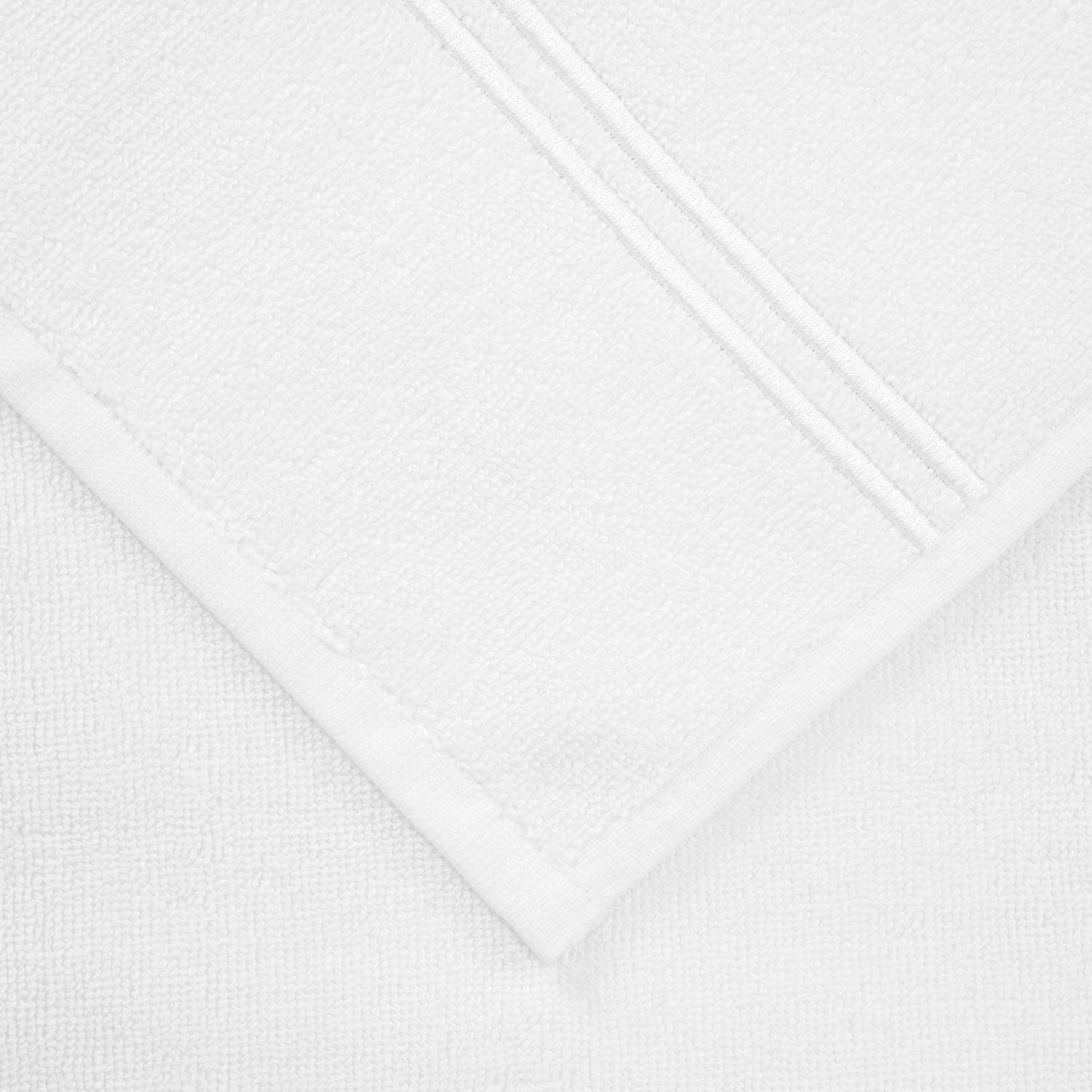 Close-up of a neatly folded towel from the Frette Classic White/White Bath Collection, crafted from soft cotton terry with decorative lines—an elegant accent for a stylish bathroom.