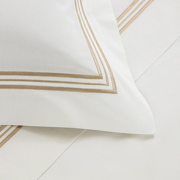 White cotton poplin pillowcase with decorative brown stripes on a pale background from the Frette Triplo Bourdon Bedding Collection.