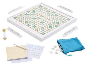 The WS Game Company's Scrabble Bianco Edition includes a wood-framed board, tiles, racks spelling "SEASIDE" and "COASTAL," plus a scorepad, hourglass timer, and a blue tile bag with an ocean breeze design.