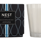 A Nest Ocean Mist & Sea Salt Candle from the Candle Collection sits in a striped glass holder beside its black and blue packaging, infusing the air with a refreshing ocean mist and sea salt aroma.