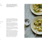 Two plates of crispy gnocchi with corn, ricotta, and spinach—garnished with herbs—sit atop a white table, accompanied by a small bowl of pepper and a glass of water; the perfect setting inspired by “A Meal For Two” from Chronicle Books.
