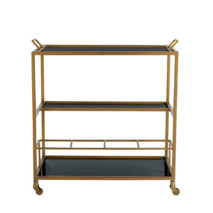 Arteriors Jak Bar Cart in Antique Brass, a three-tier antique brass cart featuring black glass trays, a metal frame, and casters.