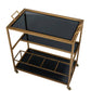 Arteriors Jak Bar Cart in Antique Brass, a three-tier design featuring black glass trays, handles, and caster wheels.