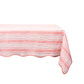 A rectangular table covered with a breezy linen tablecloth from the Juliska Cabana Stripe Collection, featuring red and white stripes, is elegantly positioned against a stark white background.