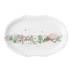 The Juliska Berry & Thread North Pole Collection features an oval ceramic platter with a winter scene—colorful houses, trees, mountains, and skaters—perfect for festive table settings or Christmas plate displays.