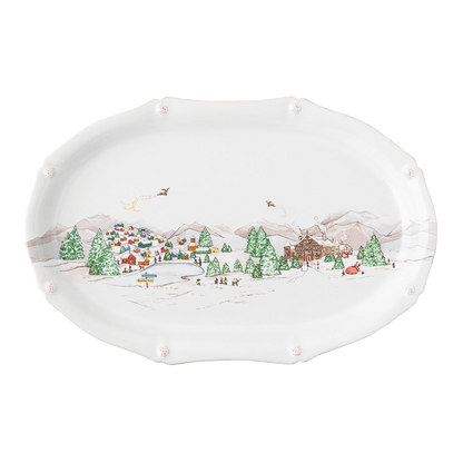 The Juliska Berry & Thread North Pole Collection features an oval ceramic platter with a winter scene—colorful houses, trees, mountains, and skaters—perfect for festive table settings or Christmas plate displays.