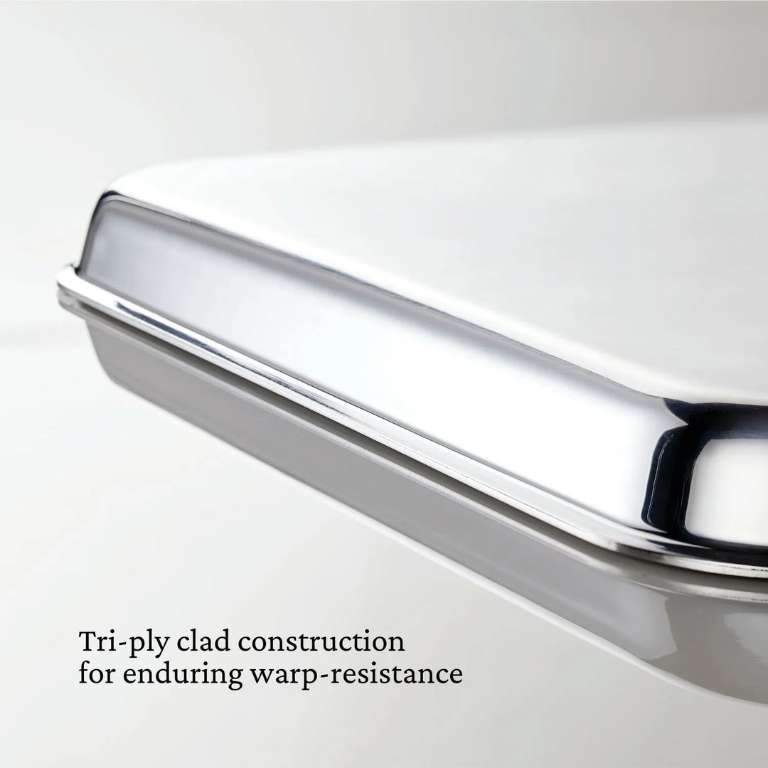 Close-up of a shiny stainless steel lid from the Hestan Provisions OvenBond Tri-ply 3-Piece Set, featuring text: "Tri-ply clad construction ensures lasting, warp-resistant performance—ideal for your Half Sheet Pan.