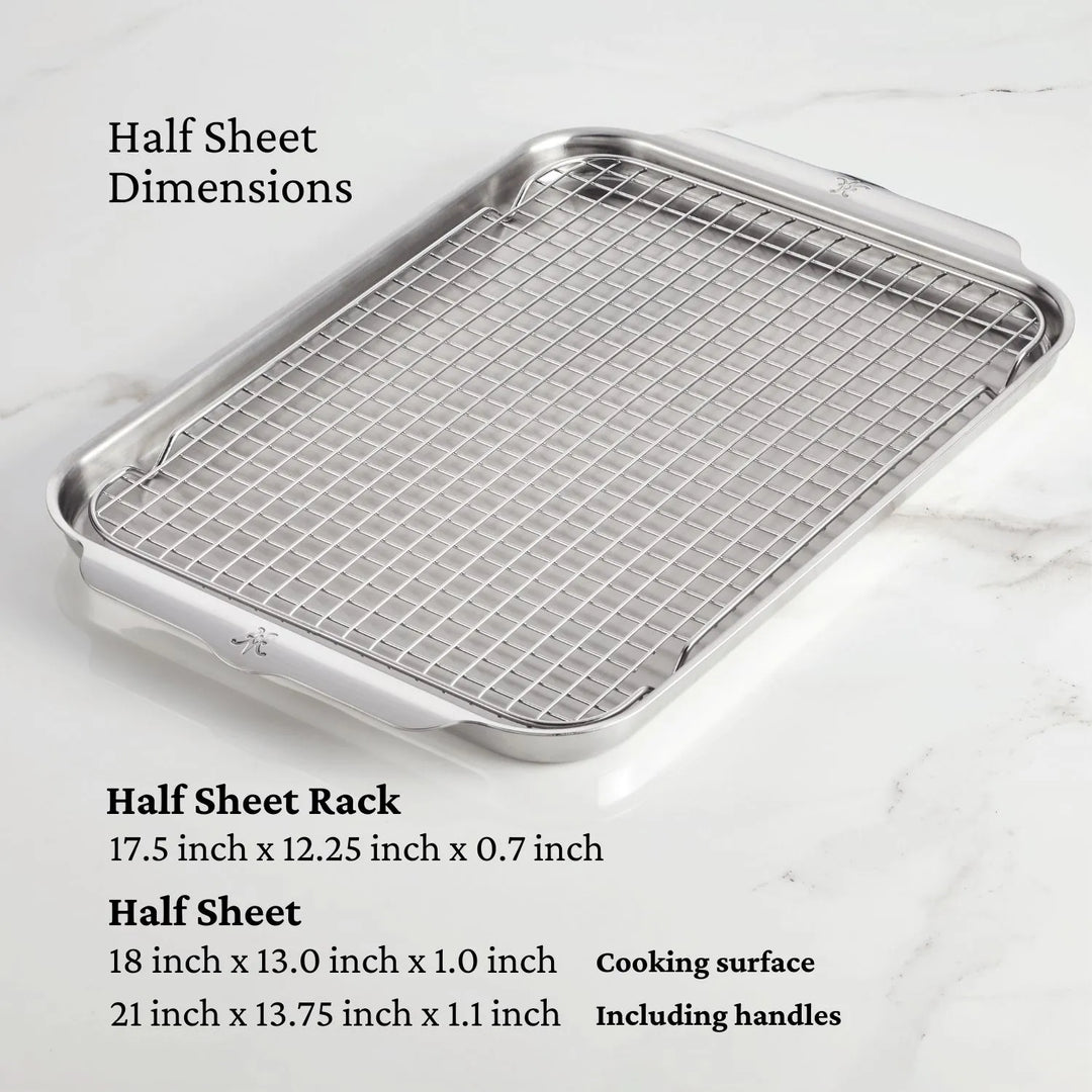 The Hestan Provisions OvenBond Tri-ply 3-Piece Set, featuring a warp-resistant half sheet pan and stainless steel rack with listed dimensions, rests on a marble surface.