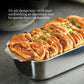 A golden-brown pull-apart bread loaf rests in a Hestan Provisions OvenBond Tri-ply Stainless Steel Loaf Pan, its superior heat conductivity ensuring even baking and perfectly sprinkled herbs on top.