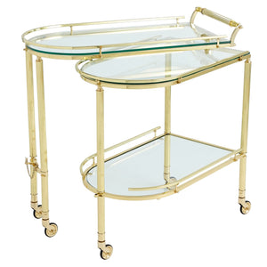 The Global Views Gallery Folding Bar in shiny brass features two tempered glass shelves, curved edges, a handle, and four caster wheels for mobility.