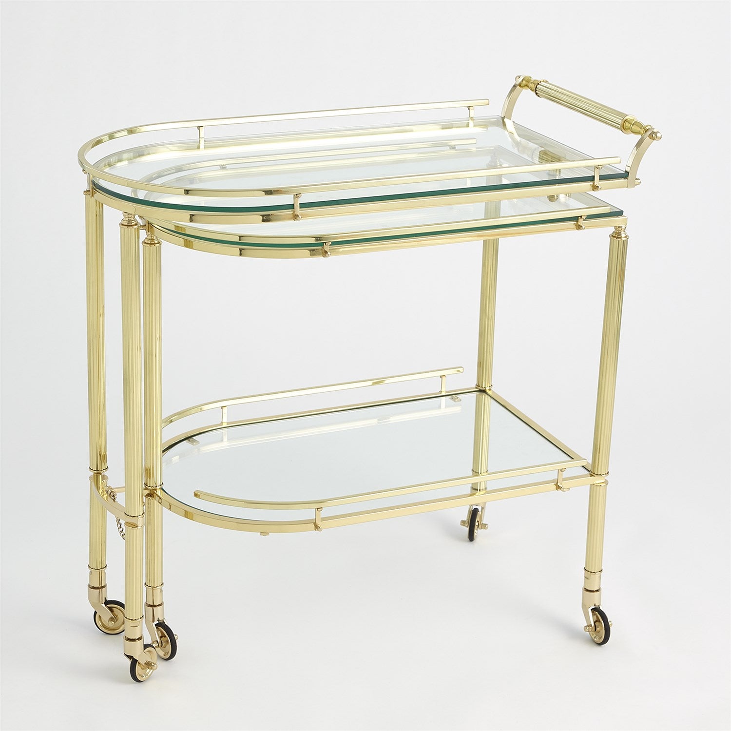 The Gallery Folding Bar Shiny Brass by Global Views features two glass shelves, curved edges, solid brass handles, and four wheels for mobility.