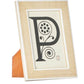 A framed monogram of the letter 'p' with decorative elements on a stand, crafted from Pigeon & Poodle Aberdeen Frame Collection and Narra veneer wood.